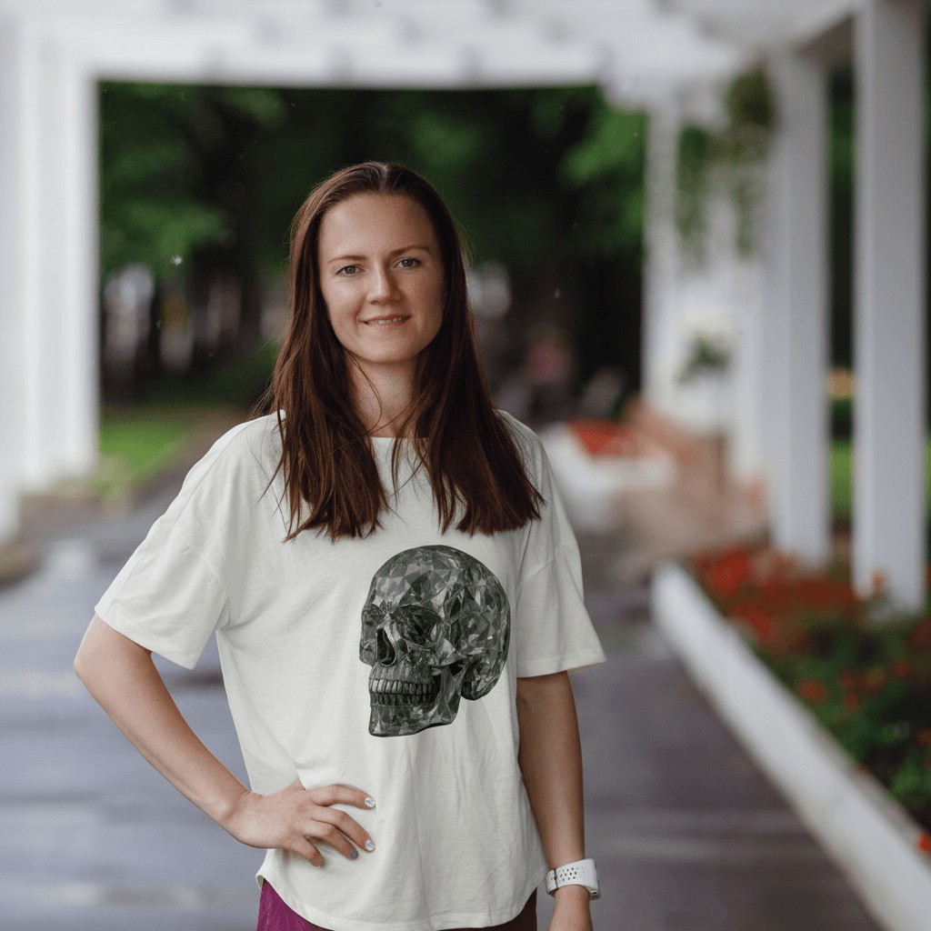 Дівчина у білій футболці EvilDOC із принтом черепа стоїть на вулиці